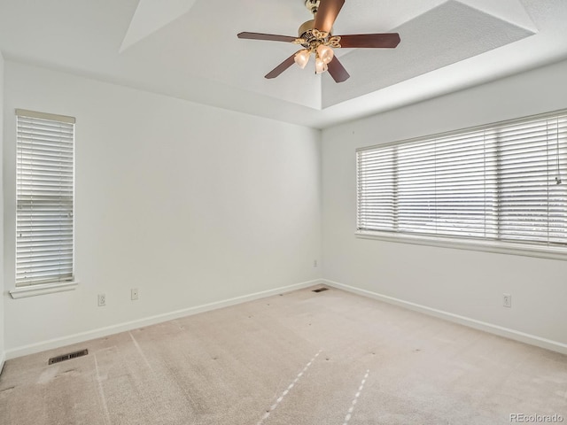 carpeted spare room featuring a raised ceiling and ceiling fan