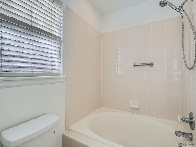 bathroom featuring tiled shower / bath combo and toilet