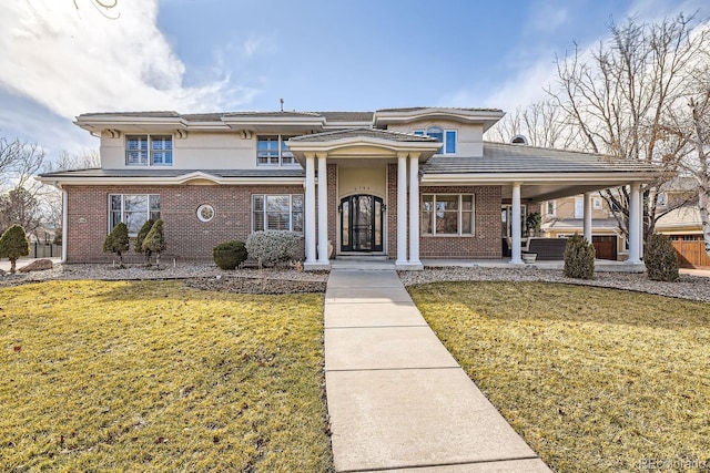 view of front of property with brick siding, a front yard, and stucco siding