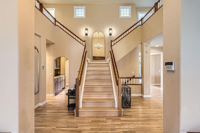 staircase featuring a wealth of natural light, baseboards, a high ceiling, and wood finished floors