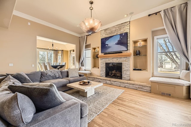 living area featuring ornamental molding, a wealth of natural light, a fireplace, and wood finished floors