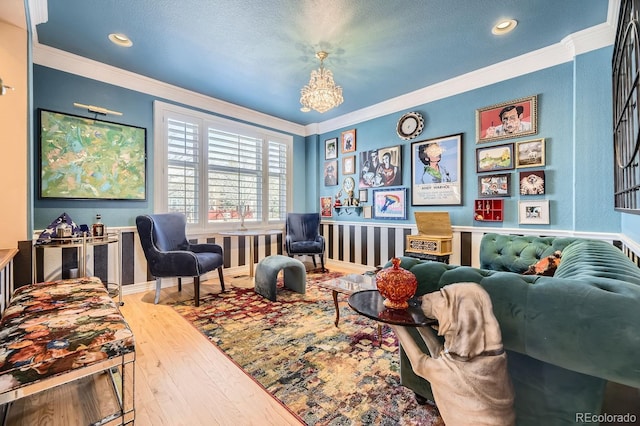 living area with a chandelier, crown molding, and wood finished floors