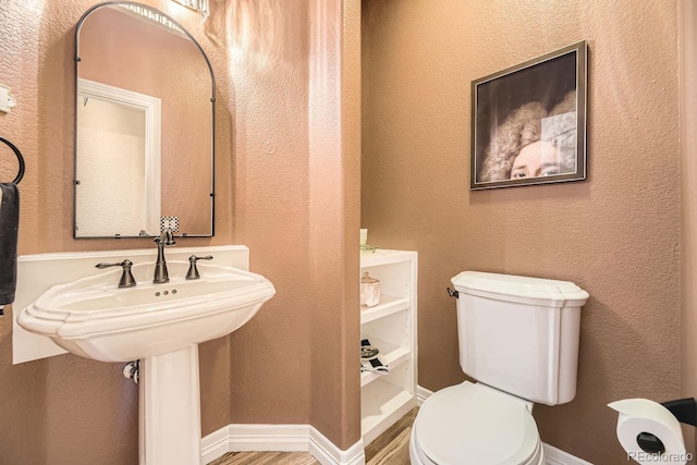 half bathroom with baseboards, a textured wall, toilet, and wood finished floors