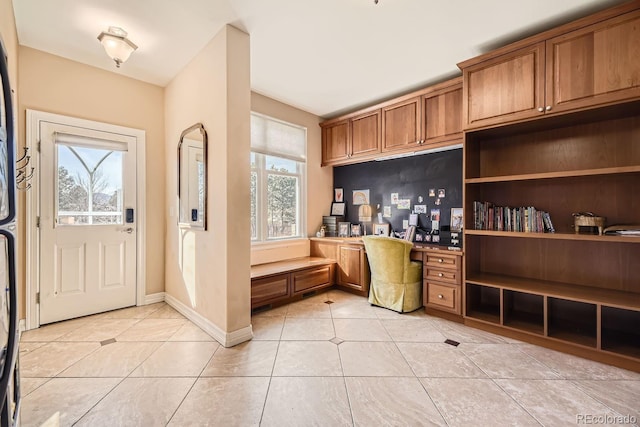 entryway featuring built in desk, light tile patterned flooring, and baseboards