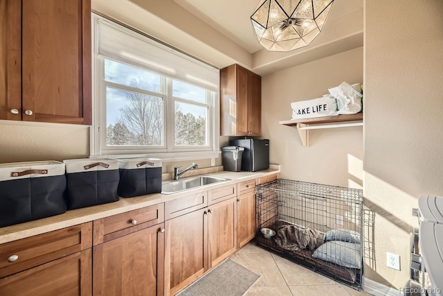 kitchen featuring brown cabinets, open shelves, light tile patterned floors, light countertops, and a sink