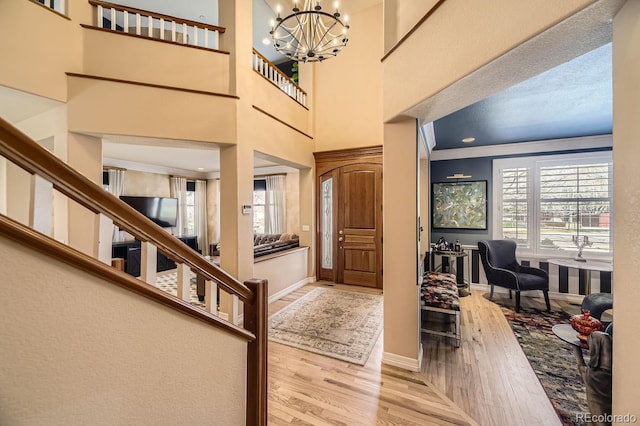 entryway featuring a towering ceiling, an inviting chandelier, baseboards, and wood finished floors