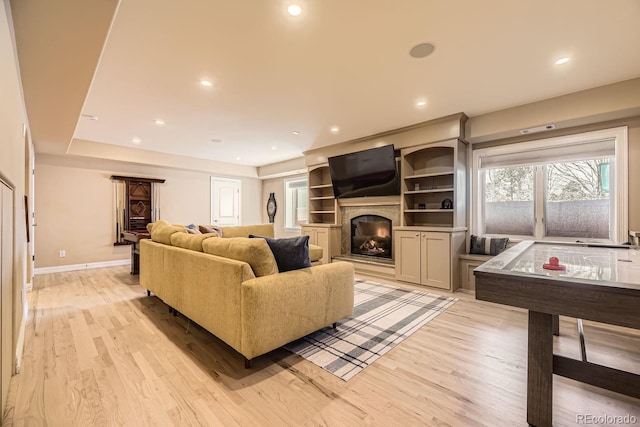 living area featuring a glass covered fireplace, baseboards, light wood finished floors, and recessed lighting