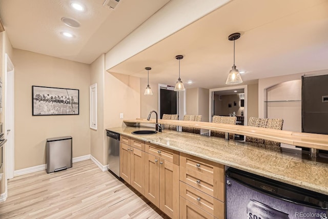 kitchen featuring pendant lighting, light wood finished floors, a sink, light stone countertops, and dishwasher