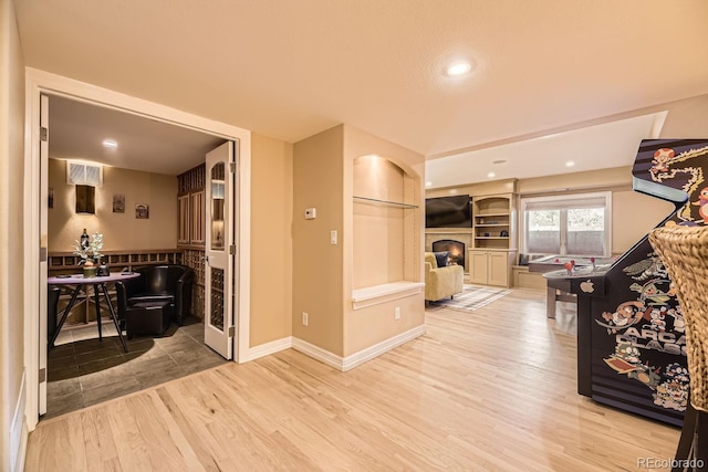 interior space with a warm lit fireplace, baseboards, visible vents, and wood finished floors