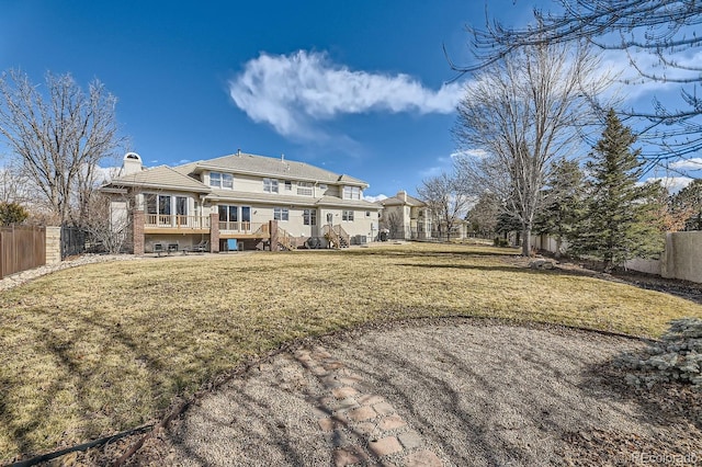 back of house featuring a fenced backyard, a yard, a chimney, and a wooden deck