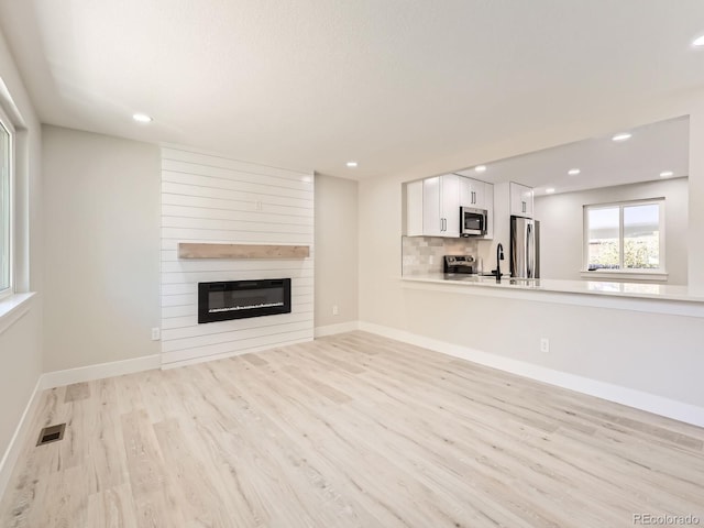 unfurnished living room with a fireplace, light hardwood / wood-style flooring, and sink