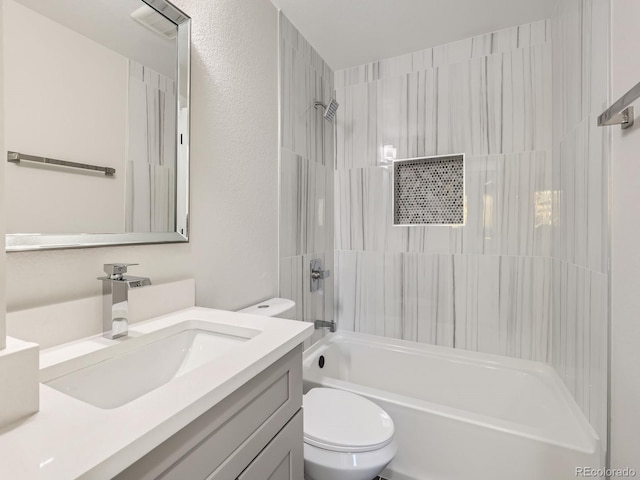 full bathroom featuring vanity, tiled shower / bath, and toilet