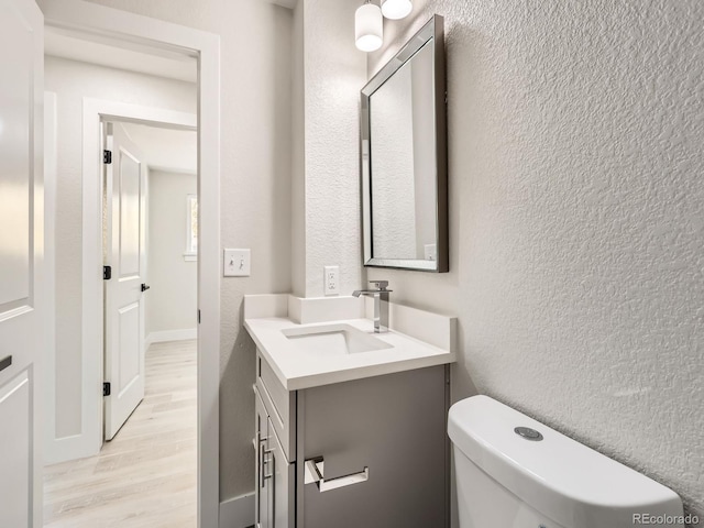 bathroom featuring hardwood / wood-style flooring, vanity, and toilet