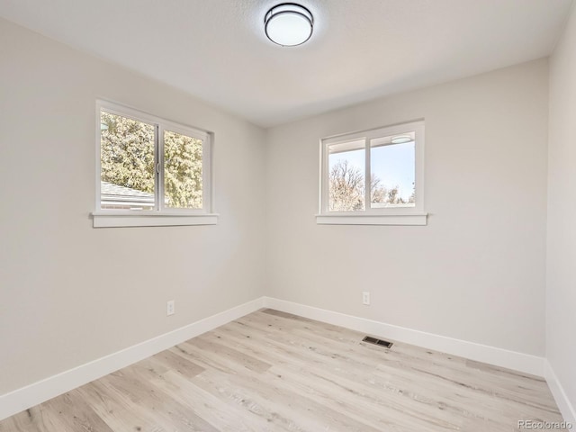 spare room featuring a healthy amount of sunlight and light hardwood / wood-style floors