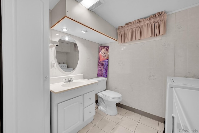 5621 Demott Ave, Commerce City, CO 80022 - bathroom with washer / clothes dryer, tile walls, tile patterned flooring, vanity, and toilet