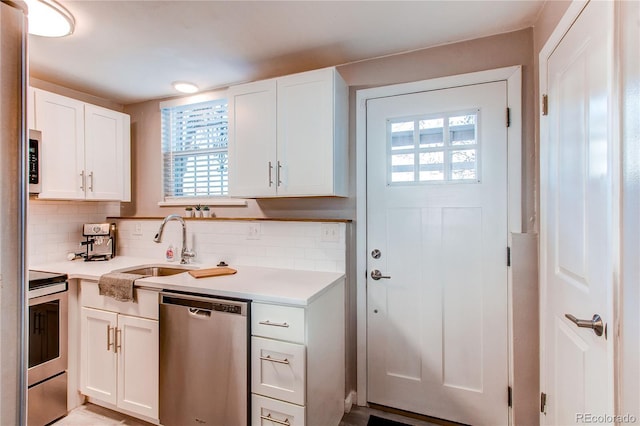 kitchen with stainless steel appliances, plenty of natural light, white cabinetry, and a sink