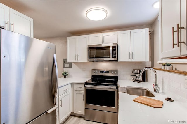 kitchen with light countertops, appliances with stainless steel finishes, a sink, and white cabinets