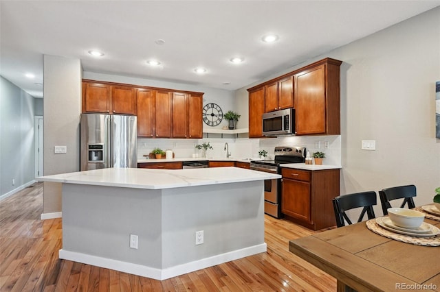 3482 E 28th Ave, Denver, CO 80205 - kitchen featuring stainless steel appliances, a sink, backsplash, a center island, and light wood-type flooring
