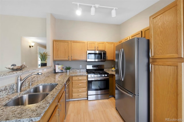 kitchen featuring stainless steel appliances, sink, light stone counters, and kitchen peninsula