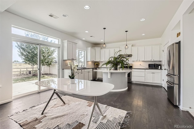 5010 Eaglewood Ln, Johnstown, CO 80534 - kitchen with stainless steel appliances, a kitchen island, recessed lighting, dark wood-type flooring, and decorative backsplash
