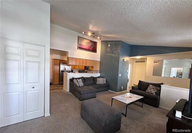 carpeted living area with rail lighting, visible vents, a textured ceiling, high vaulted ceiling, and baseboards