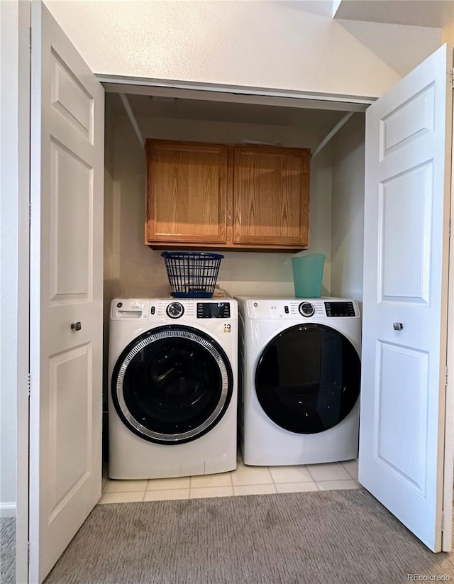 clothes washing area featuring cabinet space, light tile patterned floors, and washer and dryer