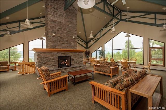 living room featuring ceiling fan, a towering ceiling, a stone fireplace, and carpet flooring