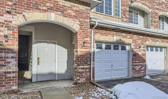 property entrance featuring an attached garage and brick siding