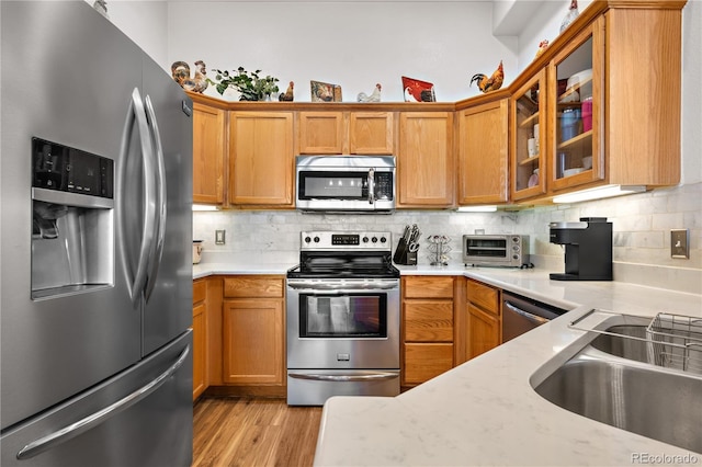 8944 Fox Dr Unit 6-103, Denver, CO 80260 - kitchen with stainless steel appliances, decorative backsplash, glass insert cabinets, and light wood-type flooring
