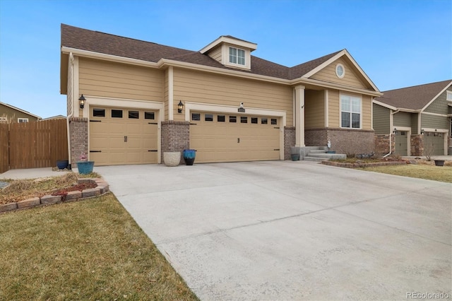 view of front facade with an attached garage, fence, concrete driveway, and brick siding