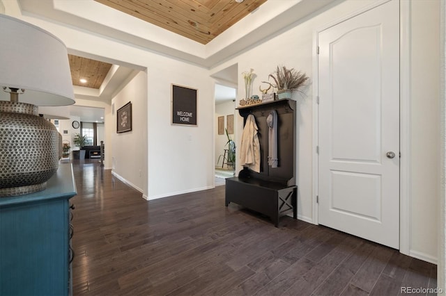 corridor featuring dark wood-style floors, baseboards, and a raised ceiling