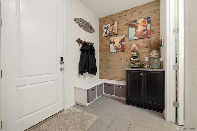 mudroom featuring light tile patterned floors and wooden walls