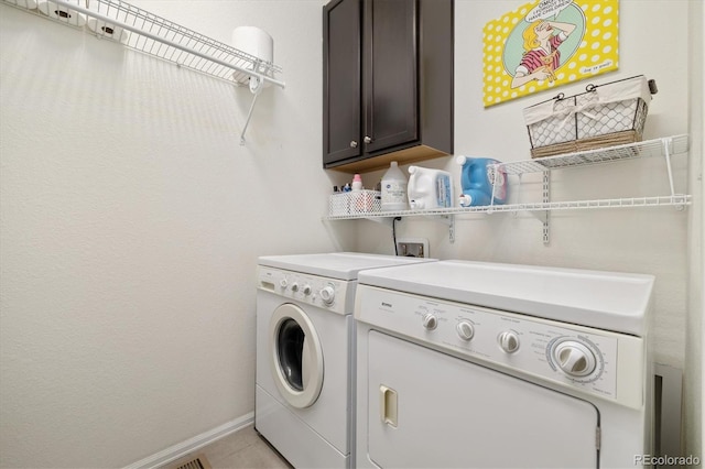 washroom with cabinet space, washing machine and dryer, baseboards, and light tile patterned flooring