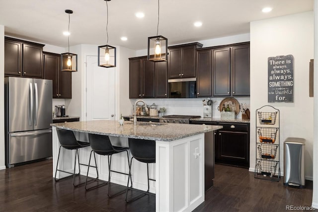 kitchen with light stone counters, dark brown cabinetry, a sink, freestanding refrigerator, and dark wood-style floors