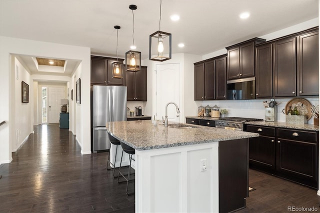 kitchen with dark brown cabinetry, appliances with stainless steel finishes, a kitchen breakfast bar, and a sink