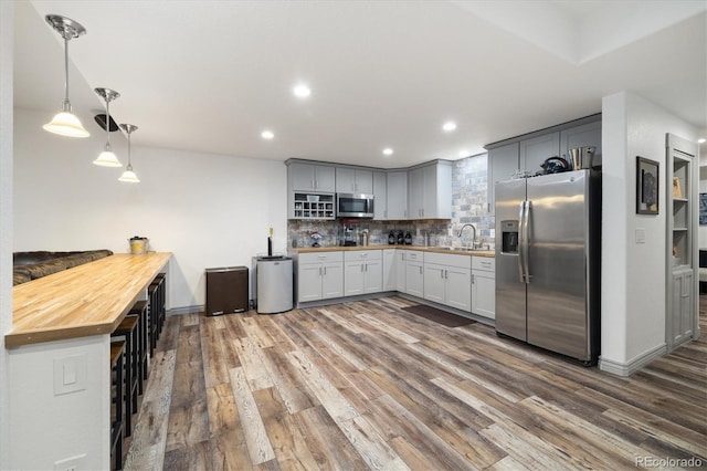 kitchen with pendant lighting, stainless steel appliances, recessed lighting, tasteful backsplash, and wood finished floors