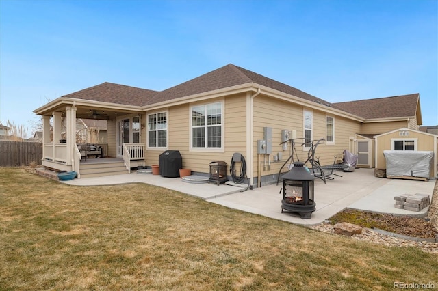 rear view of house with a yard, a patio, a ceiling fan, fence, and a fire pit