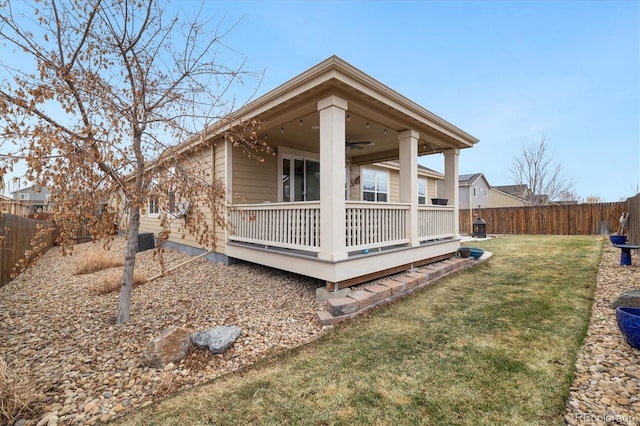 back of house featuring ceiling fan, a fenced backyard, a deck, and a yard