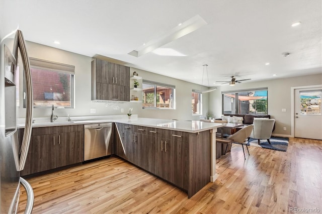 kitchen with ceiling fan, sink, kitchen peninsula, light hardwood / wood-style flooring, and appliances with stainless steel finishes