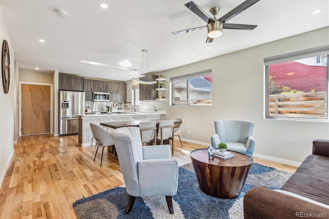 living room featuring ceiling fan, light wood-type flooring, and a healthy amount of sunlight