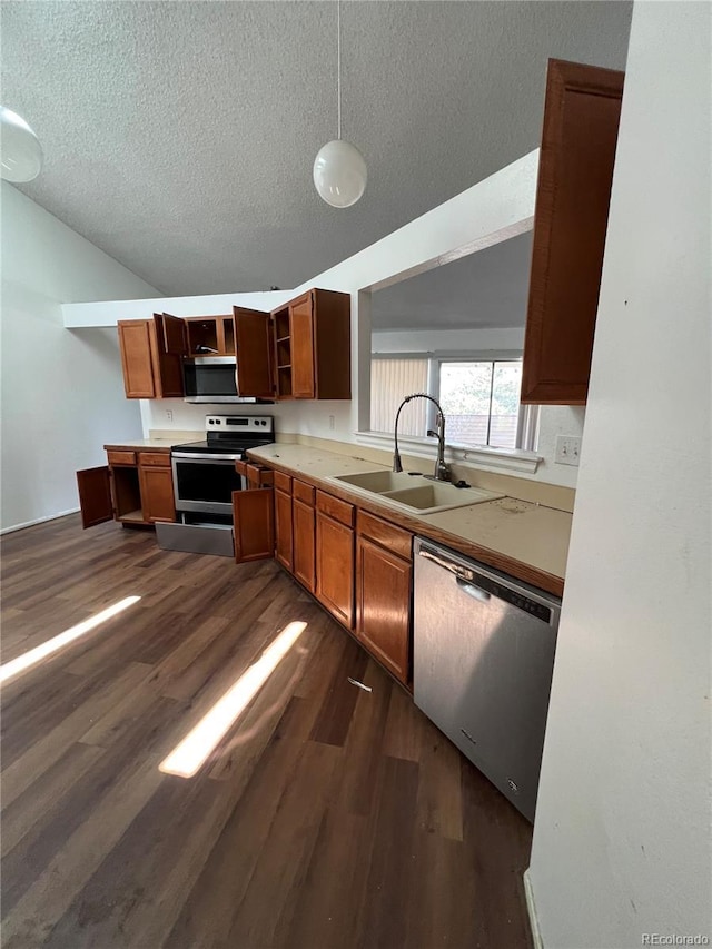 kitchen featuring a textured ceiling, stainless steel appliances, dark wood-type flooring, sink, and hanging light fixtures