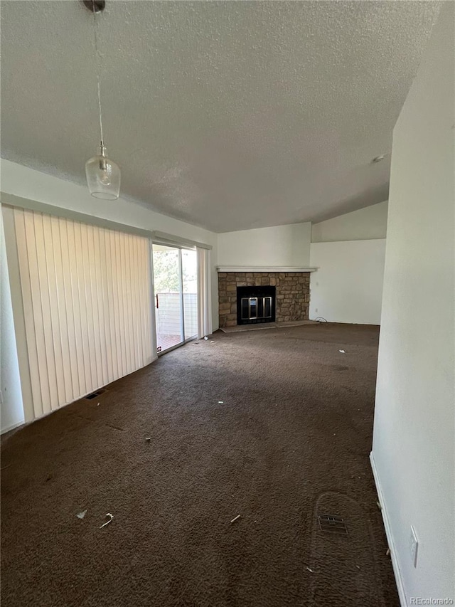 unfurnished living room featuring vaulted ceiling, a fireplace, dark carpet, and a textured ceiling