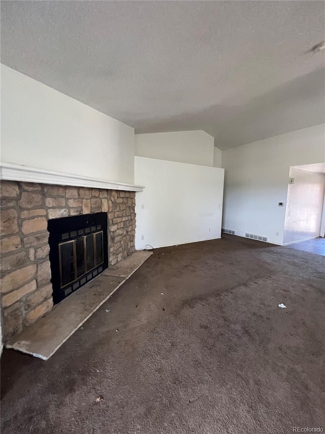 unfurnished living room featuring a textured ceiling, a stone fireplace, and vaulted ceiling