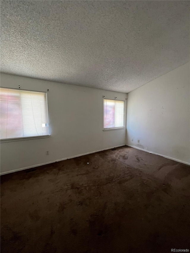 carpeted empty room featuring a textured ceiling