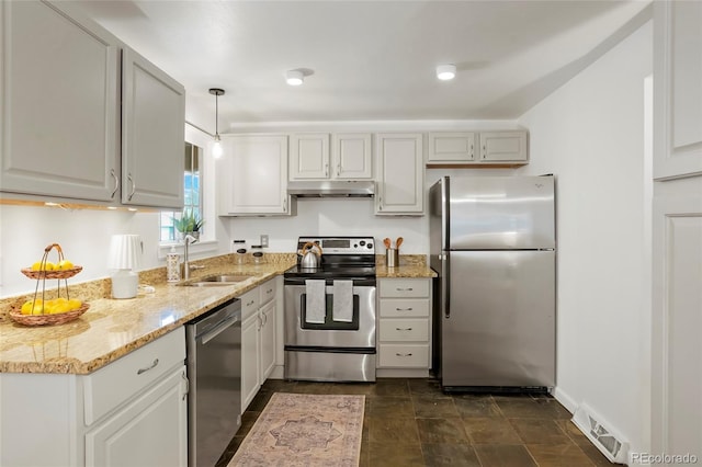 kitchen featuring sink, light stone countertops, hanging light fixtures, and appliances with stainless steel finishes