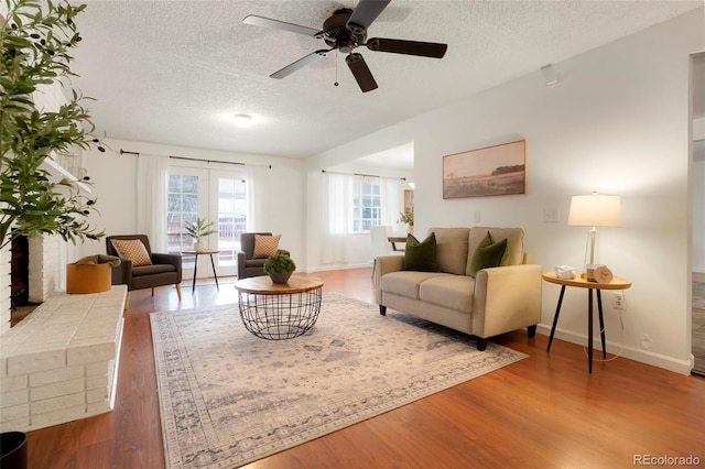 living room featuring wood-type flooring, ceiling fan, and a textured ceiling