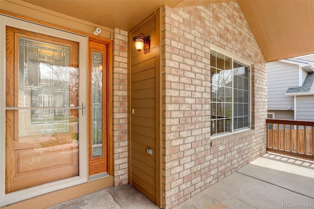 view of exterior entry with brick siding and covered porch