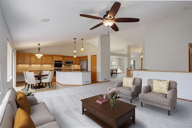 living area with lofted ceiling, light carpet, ceiling fan, and baseboards