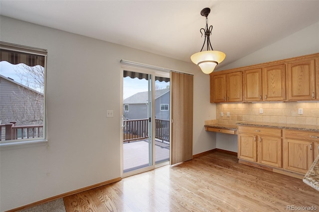 kitchen with tasteful backsplash, light wood-type flooring, pendant lighting, baseboards, and lofted ceiling