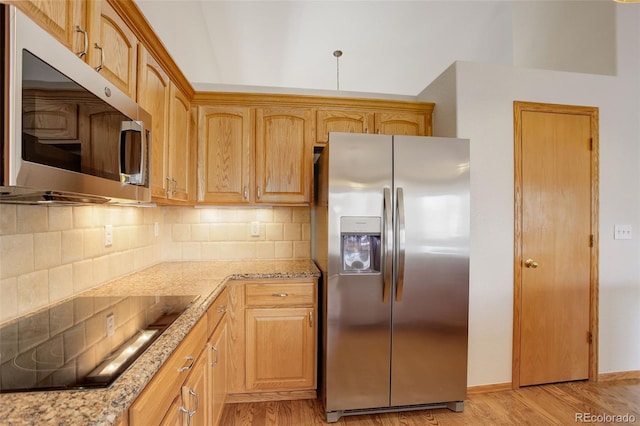 kitchen with stainless steel appliances, backsplash, light wood-type flooring, and light stone counters